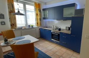 ビンツにあるVilla Hildegard Appartement 4のキッチン(青いキャビネット、テーブル、椅子付)