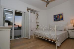 a bedroom with a white bed and a sliding glass door at ΑΙΩΡΑ in Mikonos