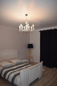 um quarto com uma cama branca e um lustre em Le gîte de la palmeraie em Étauliers