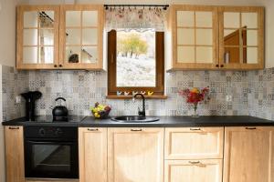 kuchnia z drewnianymi szafkami, umywalką i oknem w obiekcie Słoneczna Chałupka w Zawoi