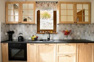 a kitchen with wooden cabinets and a sink and a window at Słoneczna Chałupka in Zawoja