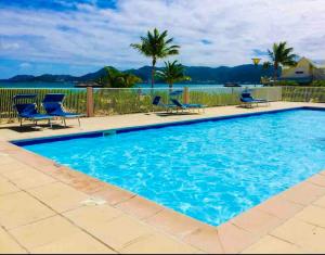 Una piscina con sillas y el océano al fondo. en Blue Dream 3 à 5 chambres villa sur la plage, en Baie Nettle