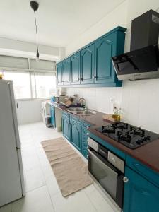 a kitchen with blue cabinets and a stove top oven at Blue Bay Apartment in Setúbal