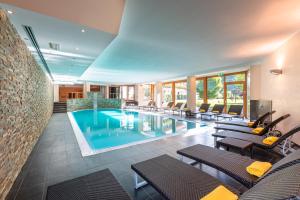 a pool in a hotel with chairs and tables at Hotel La Perla in Ravascletto