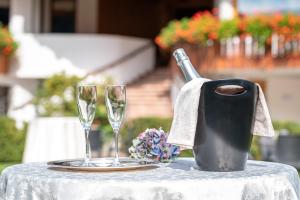 einen Tisch mit zwei Weingläsern und einer Wasserkanne in der Unterkunft Hotel La Perla in Ravascletto