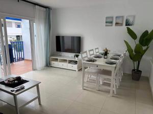 a white living room with a table and a tv at Apartamento Olivin in Puerto del Carmen