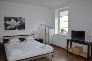 a white bedroom with a bed and a television at Vęgoria 17 Apartament przy porcie in Węgorzewo