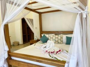 1 dormitorio con 1 cama con dosel en Frangi'pwani en Paje