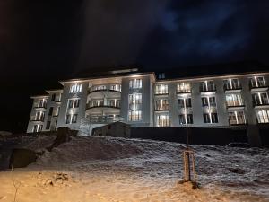 ein Gebäude in der Nacht mit Schnee davor in der Unterkunft Palace 404 in Špindlerův Mlýn