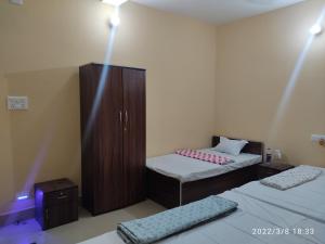 a bedroom with two beds and a wooden cabinet at KASAHARA - HOMESTAY in Bolpur
