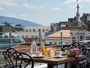 uma mesa com comida e bebidas numa varanda em Athens City View Urban Suites em Atenas