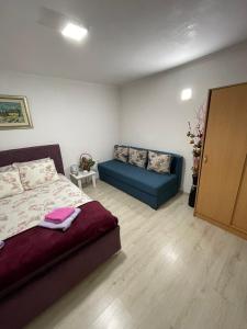 ein Schlafzimmer mit einem Bett und einem blauen Sofa in der Unterkunft JOCKER in Virpazar