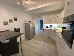 a kitchen with white cabinets and a table and a refrigerator at Ferienwohnung Traumreich in Bad Harzburg