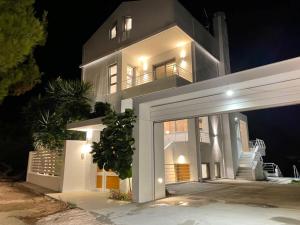 una gran casa blanca por la noche con garaje en Evaeri villa, en Artemida