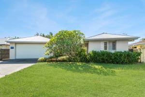 a house with a garage and a grass yard at Frangipani Hideaway in Lennox Head