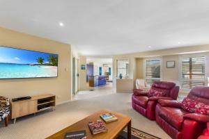 a living room with a red couch and a tv at Frangipani Hideaway in Lennox Head