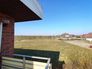 un banco sentado al lado de un edificio con un campo en Ferienwohnung am Deich, en Friedrichskoog