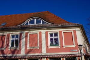 un edificio rojo y blanco con techo marrón en Cafe Alice & Pension GmbH, en Potsdam