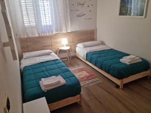 トラーパニにあるFRAiMARI Homeのベッドルーム1室(ベッド2台、ランプ付きテーブル付)