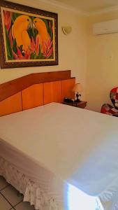 ein Schlafzimmer mit einem weißen Bett und einem Gemälde an der Wand in der Unterkunft Flat Di Roma Resort Internacional in Caldas Novas
