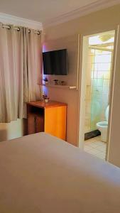 卡爾達斯諾瓦斯的住宿－Flat Di Roma Resort Internacional，一间卧室配有一张床和一台电视,还设有一间浴室