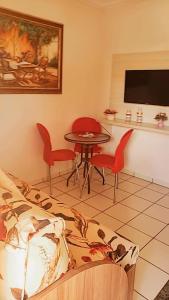 a living room with a table and red chairs at Flat Di Roma Resort Internacional in Caldas Novas