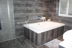 4 Bedroom Detached Holiday home with Hot Tub في ريكسهام: حمام مع حوض أبيض ودش