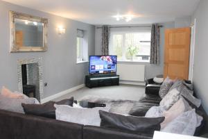 a living room with a couch and a flat screen tv at 4 Bedroom Detached Holiday home with Hot Tub in Wrexham