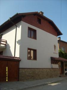 ein weißes Haus mit braunem Dach in der Unterkunft Vien Guest House in Bansko