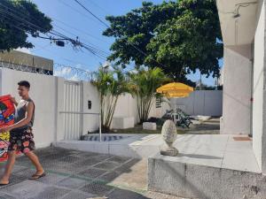 a young man walking past a house with an umbrella at Casa da Esquina Pousada in Recife