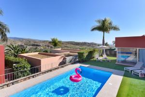 een huis met een zwembad met een roze zwaan in een tuin bij Par 4 Blue Star by VillaGranCanaria in La Playa de Arguineguín