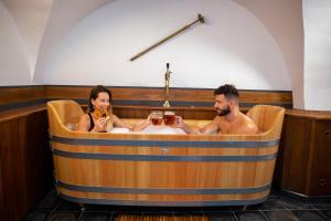 two men sitting in a bath tub with glasses of wine at U Medvidku-Brewery Hotel in Prague