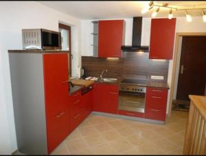 a kitchen with red cabinets and a microwave at guesthouse Elbsandstein Appartement Lilienstein in Rathmannsdorf