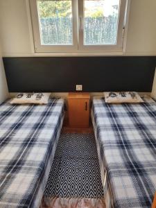 two beds in a small room with two windows at Mobil home dans camping in Saillagouse +18 photos