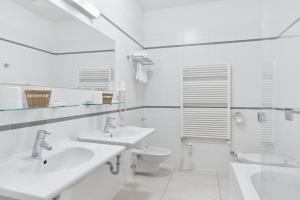 a white bathroom with two sinks and a toilet at Hotel Palatin in Karlovy Vary