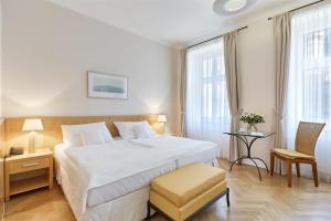 ein Schlafzimmer mit einem großen weißen Bett und einem Stuhl in der Unterkunft Hotel Palatin in Karlsbad