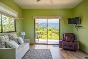 a living room with a couch and a large window at Villa Kiskadee - Beautiful Mountain Views with Private Pool & Wi-Fi in Quepos