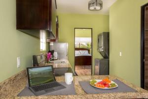 una cocina con un ordenador portátil en una encimera con una bandeja de fruta en Villa Kiskadee - Beautiful Mountain Views with Private Pool & Wi-Fi, en Quepos