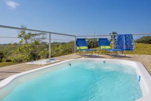 a swimming pool on a deck with two chairs at Villa Kiskadee - Beautiful Mountain Views with Private Pool in Quepos