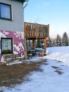 a deck with a table and benches in the snow at Bergheisl Rübenau in Rübenau