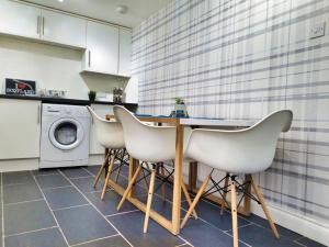 a kitchen with a table and four white chairs at The Heathers - near beach & free golf bag & clubs. in Maybole