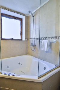 uma casa de banho com uma banheira e um chuveiro em vidro. em Cascada Del Sur em San Carlos de Bariloche
