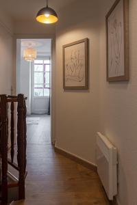 einen Flur mit einer Treppe und Gemälden an der Wand in der Unterkunft Au cœur des Remparts de Guérande: logement pour 4 in Guérande