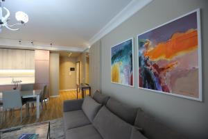 a living room with a couch and a painting on the wall at Blissful Apartments in Sarandë