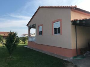 una casa con dos ventanas y un patio en Вила Маламос, en Paralía Avdhíron