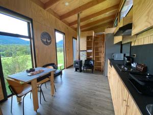 eine Küche und ein Esszimmer eines winzigen Hauses mit einem großen Fenster in der Unterkunft Aysén Lodge - Cabaña con Tinaja in Puerto Dunn