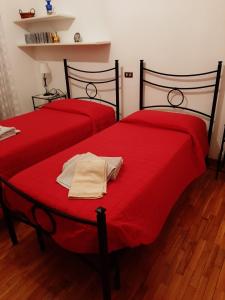 two beds with red sheets in a room at Valle degli Ulivi appartamento in Terni