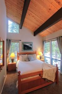 Woodsy retreat near Northstar & lake في كينغس بيتش: غرفة نوم بسرير كبير في غرفة بها نوافذ
