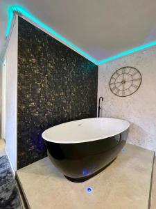 a bath tub in a bathroom with a black wall at Chabanettes Hotel & Spa in Auzelles