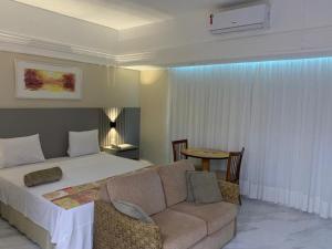 a bedroom with a bed and a couch and a table at Flat Tropical in Manaus
